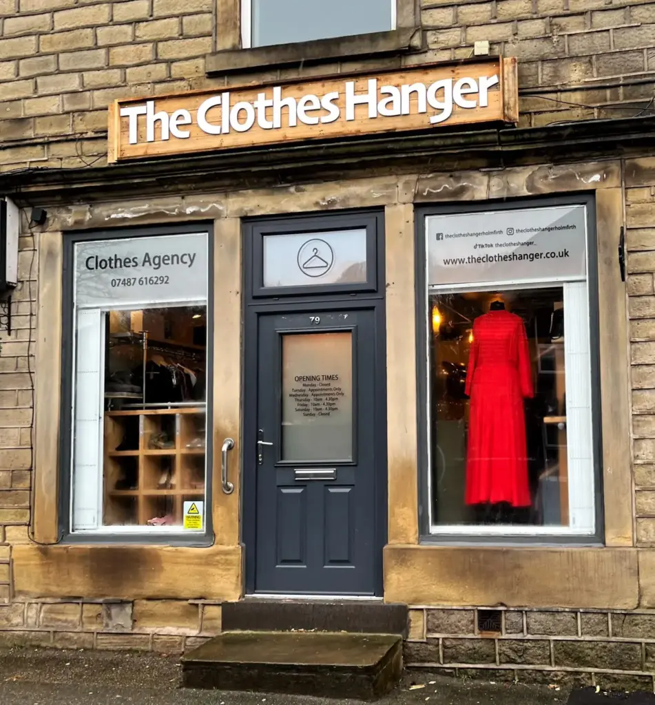 The Clothes Hanger shop front in Holmfirth, with a red dress in the window